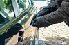 Eine Person versucht das Schloss einer Autotür aufzubrechen.
