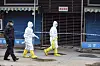 Zwei Männer in virologischen Schutzanzügen gehen durch eine leere Straße