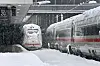 Ein ICE steht auf einem eingeschneiten Gleis am Bahnhof.