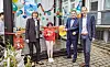 Eine Frau, ein Kind und zwei Männer schneiden ein Band durch