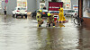 Feuerwehrmänner versuchen, eine überflutete Straße frei zu bekommen.
