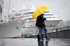 Ein Pärchen stehen unter einem Regenschirm auf der Jan-Fedder-Promenade einem Kreuzfahrtschiff