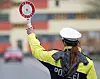 Eine Polizistin winkt mit einer Kelle ein Auto von der Straße.