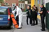 Ermittlerinnen und Ermittler befragen eine Person vor dem Haus, in dem sich der Doppelmord in Elmshorn ereignet hat.