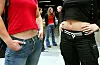 Schülerinnen stehen in bauchfreier Kleidung vor einer Schule.