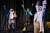 Drei skurril verkleidete Schauspieler reißen die Arme in die Luft