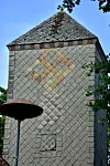 Das Hakenkreuz, gelb-orange auf grauen Schindeln, am höchsten Turm in Hönau-Lindorf