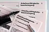 Stifte liegen auf den Arbeitsunfähigkeitsbescheinigungen für Arbeitnehmer:innen im Falle einer Krankschreibung durch Ärzte. (Symbolbild)