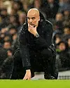 Pep Guardiola hockt auf dem Rasen und schaut nachdenklich.