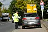 Ein Polizist kontrolliert ein graues Auto.