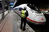 Ein Polizist steht auf einem Bahnsteig im Bahnhof Siegburg, auf dem ein ICE der Deutschen Bahn steht.