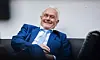 Wolfgang Kubicki sitzt lachend auf einem Sofa.