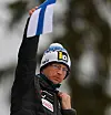 Igor Medved hält die finnische Fahne als Startsignal für einen Skisprung-Athleten hoch.