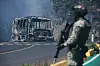 Ein Soldat steht in Cointzio neben einem ausgebrannten Bus