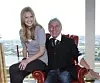 Supermodel Toni Garrn und Ted Linow bei einem Foto-Shooting 2010. Er sitzt auf einem roten Sessel, sie auf einer Armlehne. Beide lachen.